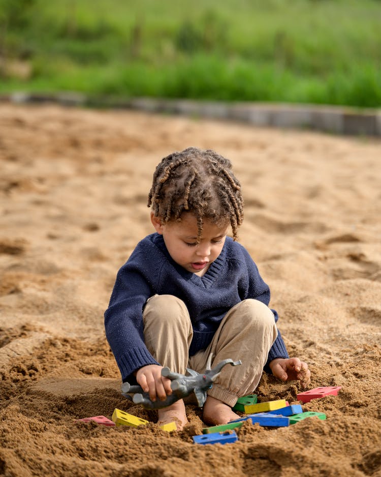 Boy Playing In The Sand With His Toys