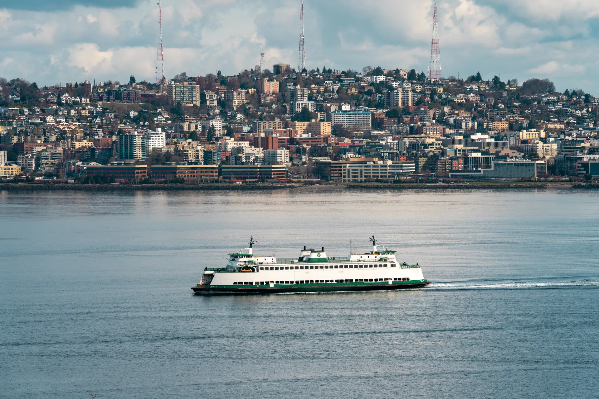 A Washington State Ferry crossing Puget Sound with the Seattle skyline behind it A Washington State Ferry crossing Puget Sound with the Seattle skyline behind it