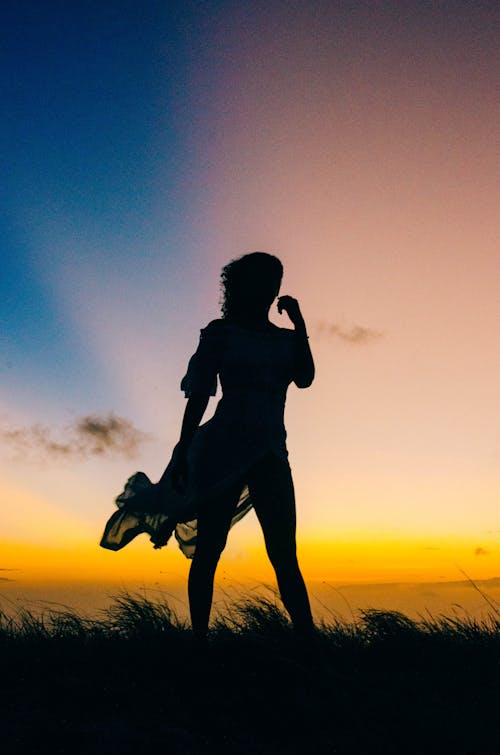Silhouette of Woman Standing on Grass