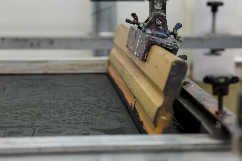 Détail d'un écran de sérigraphie textile avec sa raclette, technique alternative au flocage et à la broderie