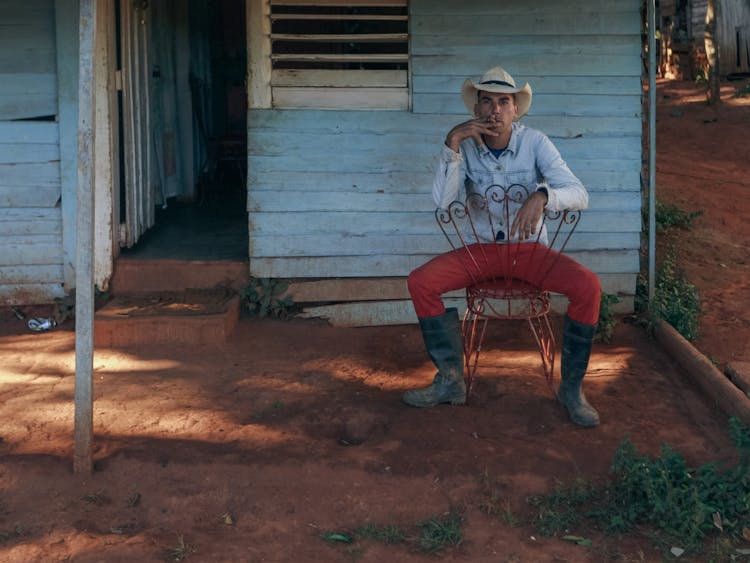 A Cowboy Smoking A Cigar While Sitting On A Chair