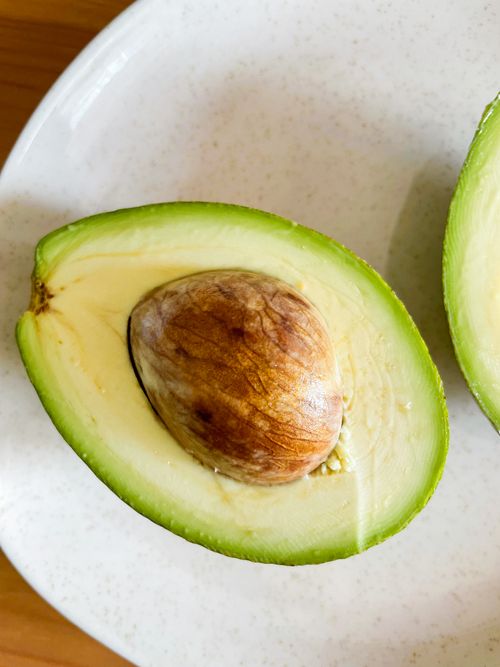 Free Close-up of fresh avocado halves on a white plate, showcasing healthy nutrition. Stock Photo