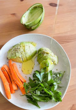 Healthy avocado salad with carrots and herbs, drizzled with oil on a white plate in Istanbul, Turkey.