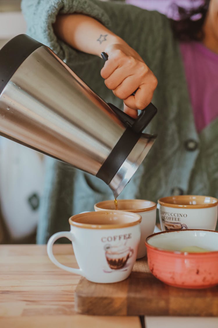 A Woman Pouring Coffee In A Ceramic Cup