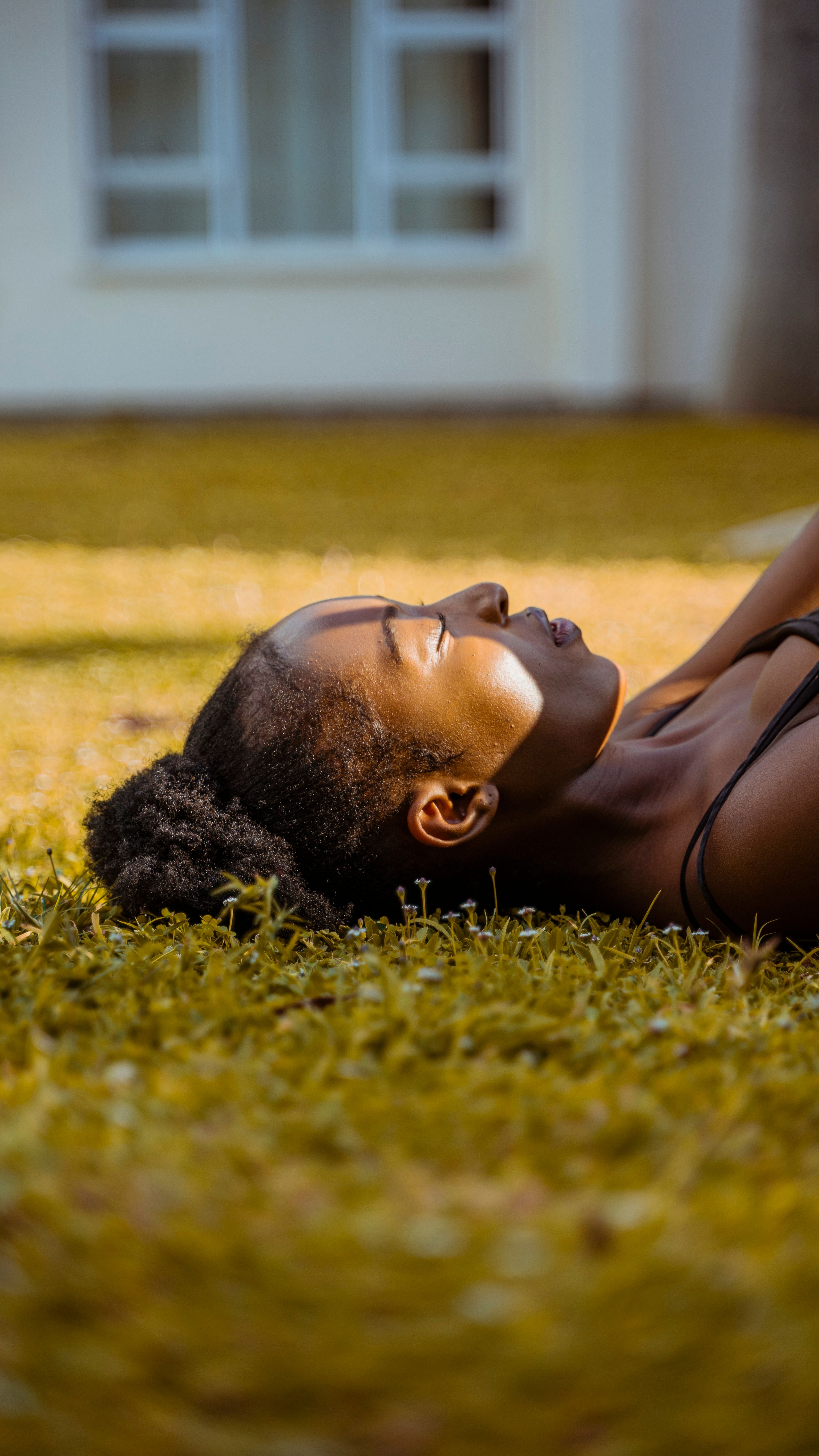 A serene portrait of a black woman lying on the grass, enjoying a peaceful moment of relaxation.