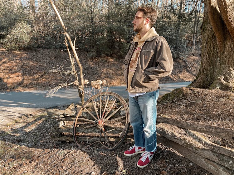 Man Next To A Wooden Wheel By The Road 