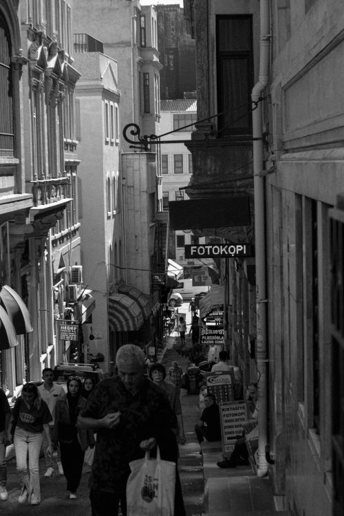 Free Black and white photo of pedestrians in a historic city street, showcasing architectural elegance. Stock Photo