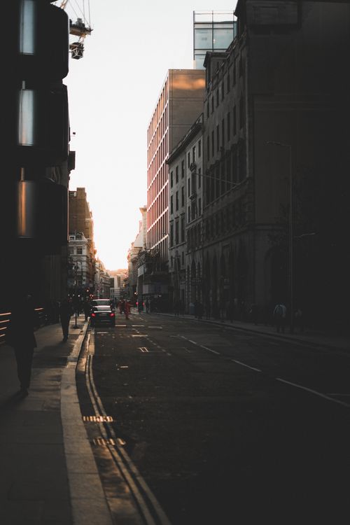 Free Moody city street scene with buildings and cars at dusk, capturing the urban vibe. Stock Photo
