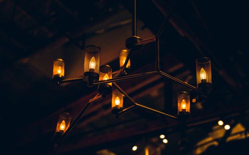 Free A modern industrial chandelier emits a warm glow in a dimly lit environment, creating a cozy atmosphere. Stock Photo