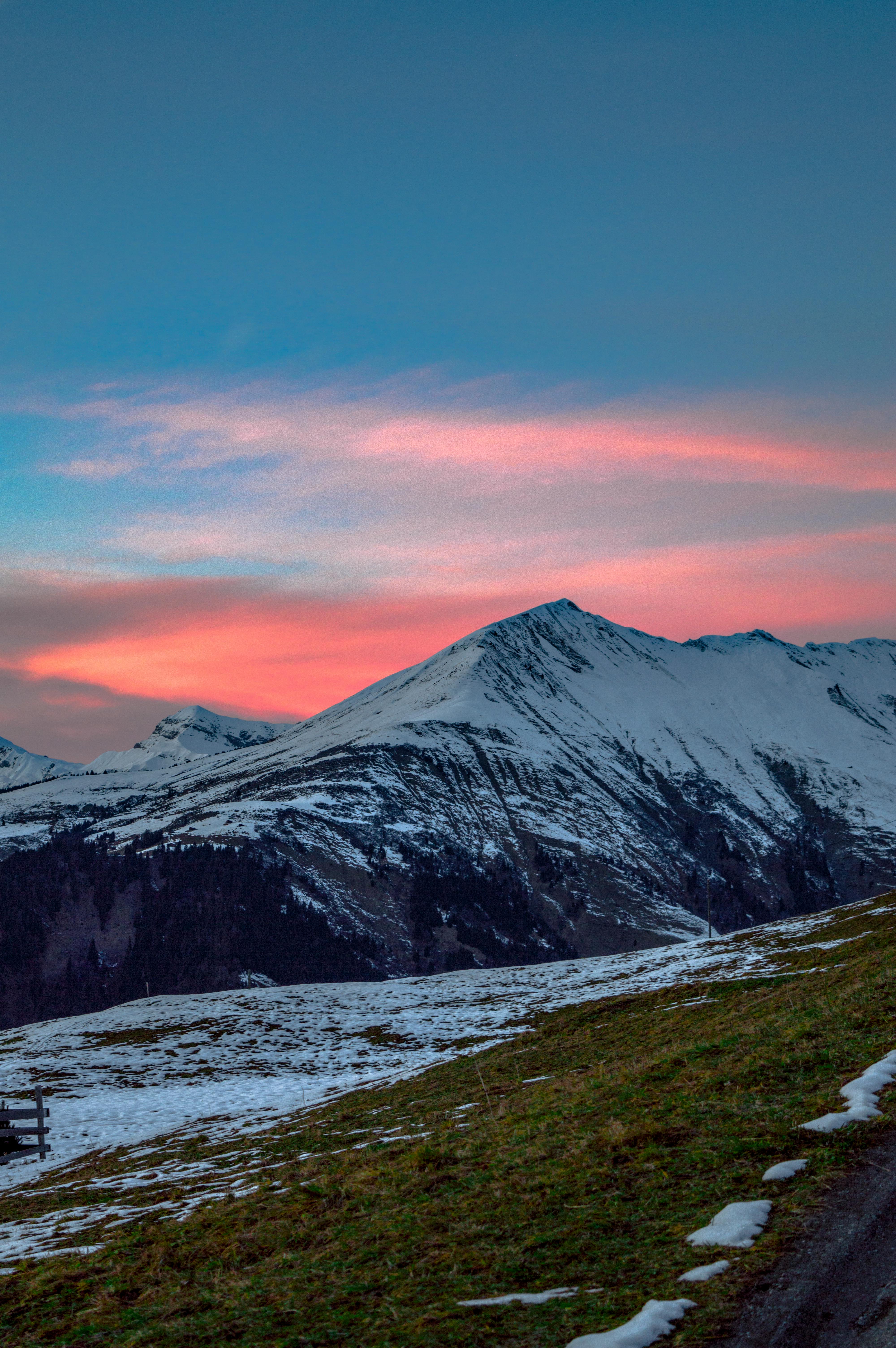 Breathtaking view of snow-capped mountains under a colorful twilight sky, perfect for nature enthusiasts.