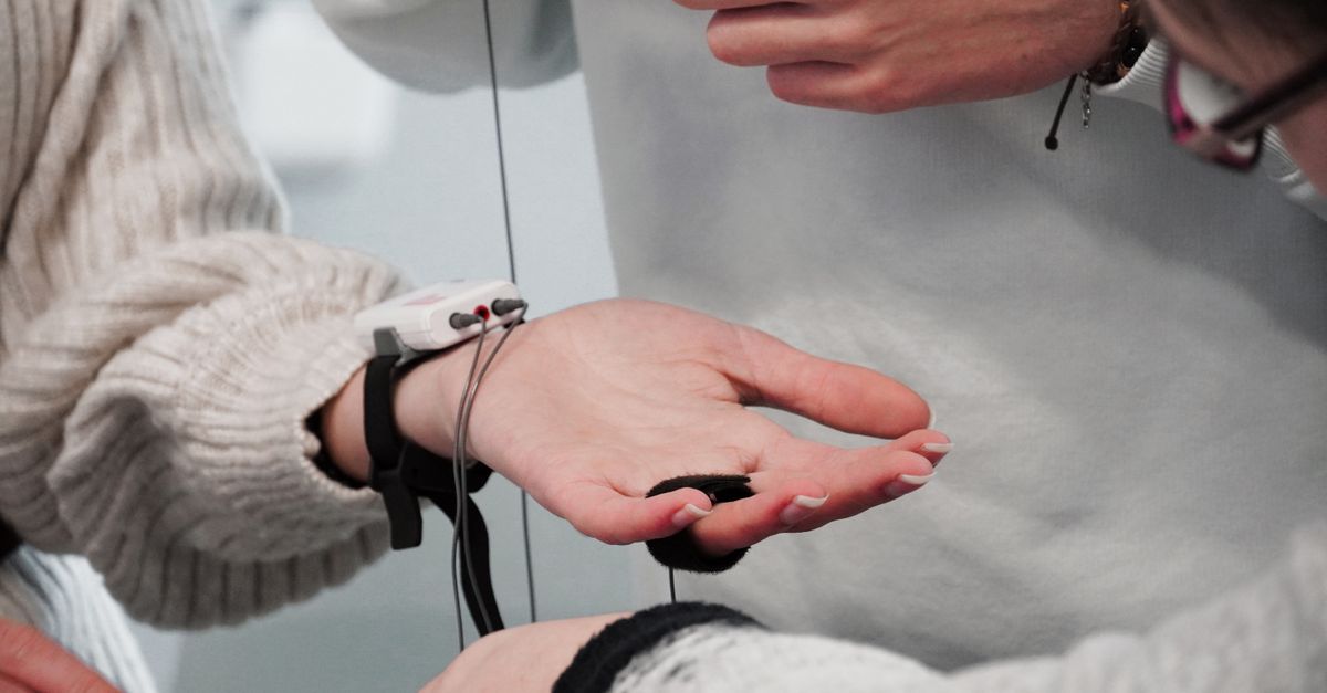 Detailed view of hands interacting with electronic device, showcasing technology and collaboration.