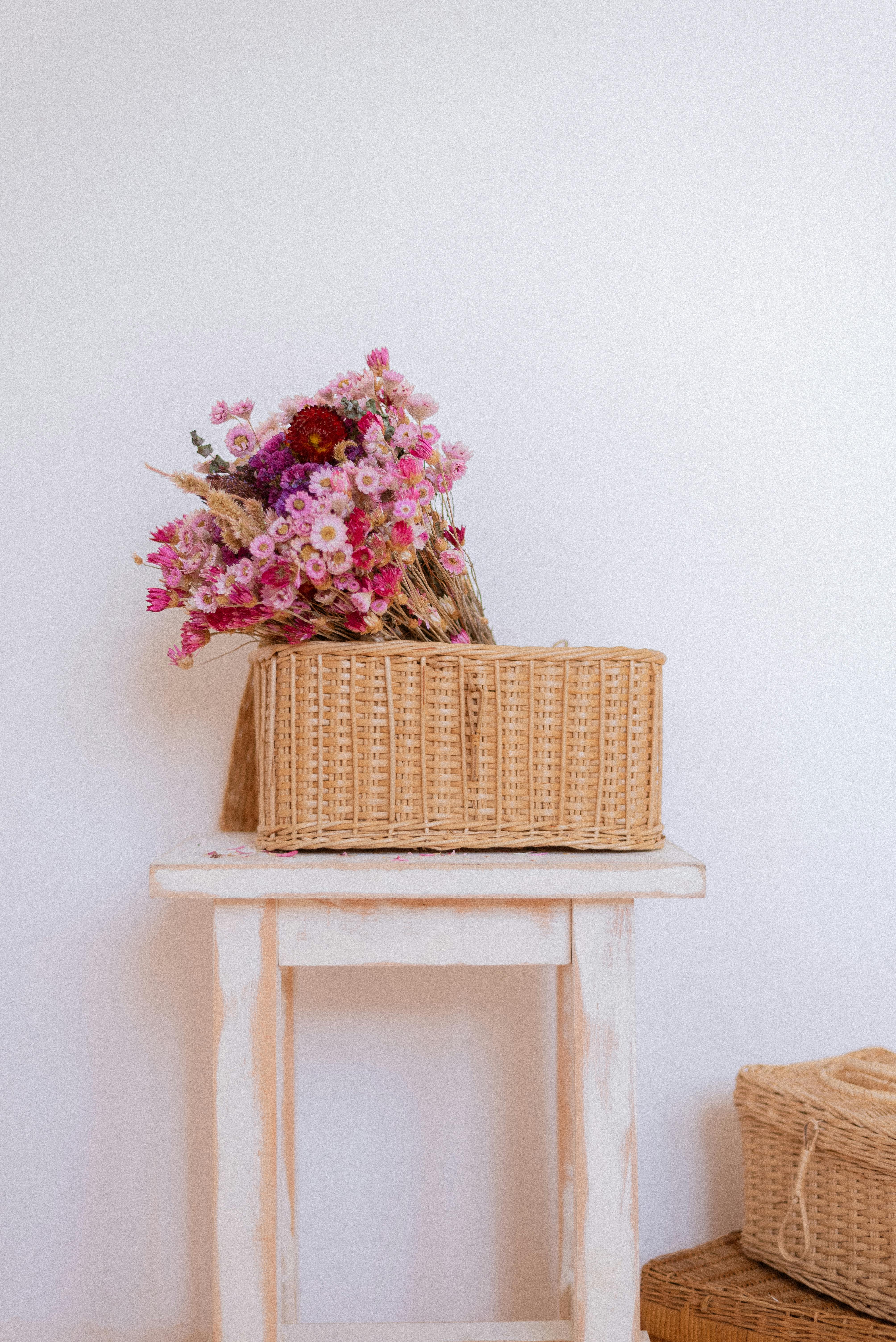 Elegant home decor featuring a wicker basket with dried flowers on a rustic stool.