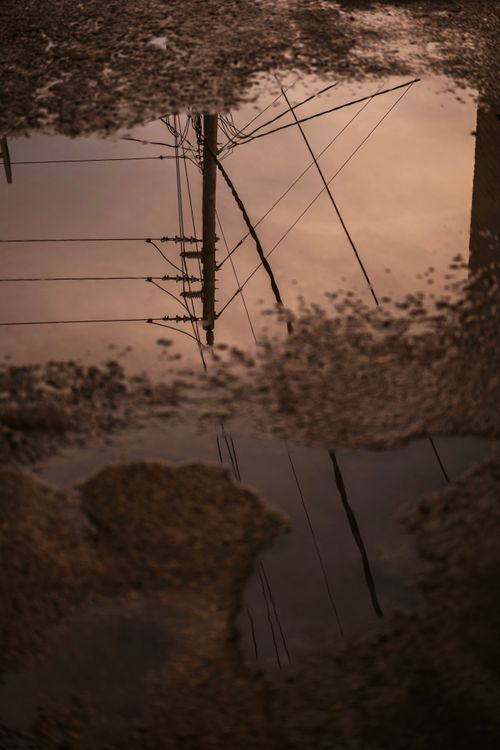 Free Moody reflection of power cables in a street puddle after rain. Stock Photo