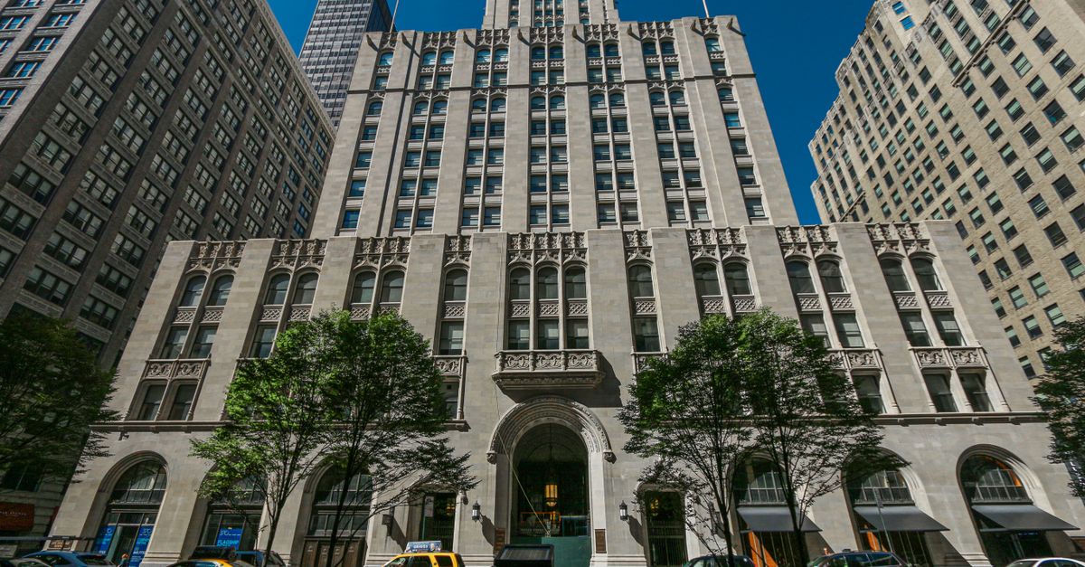 Architectural view of a historic skyscraper in New York City's downtown district on a sunny day.