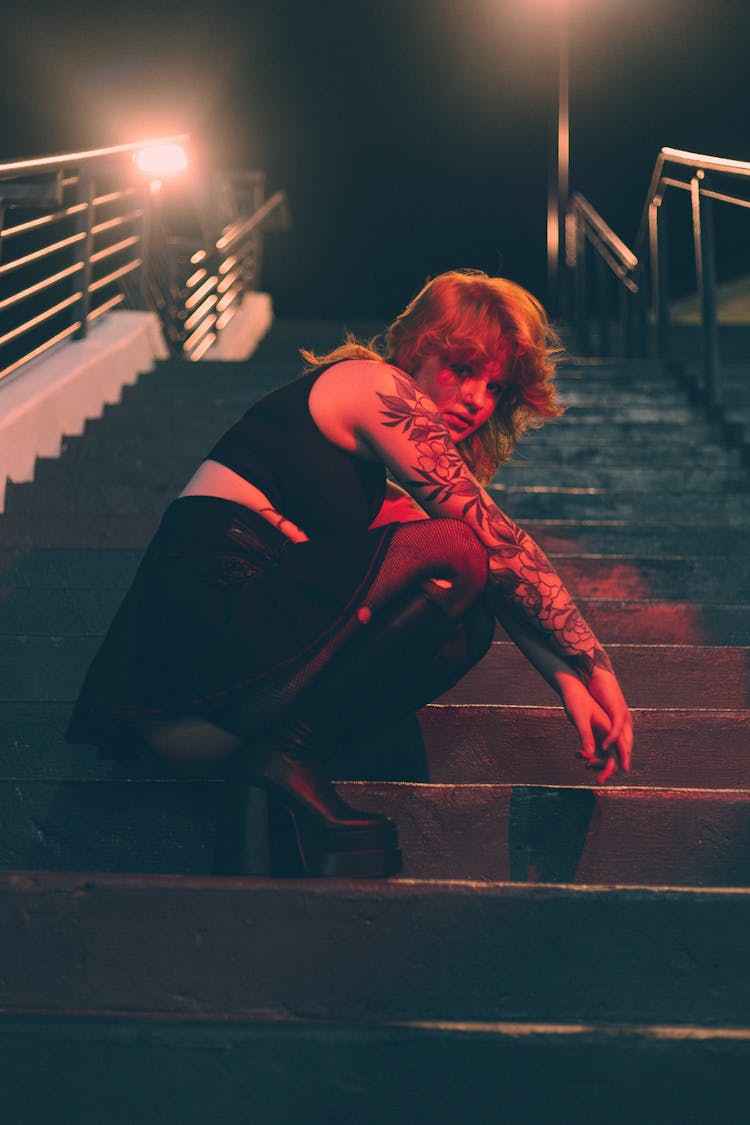 Girl With Tattoos Sitting On Stairs In Dark