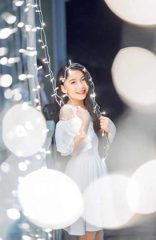 Free A young woman poses with fairy lights, creating a dreamy and glowing atmosphere indoors. Stock Photo