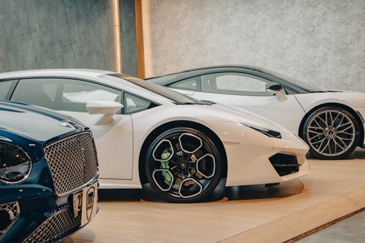 A lineup of sleek luxury sports cars on display in an upscale showroom setting.
