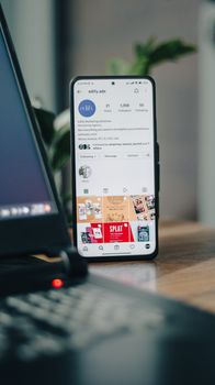 Vertical shot of a smartphone displaying an Instagram profile next to a laptop, representing social media engagement.