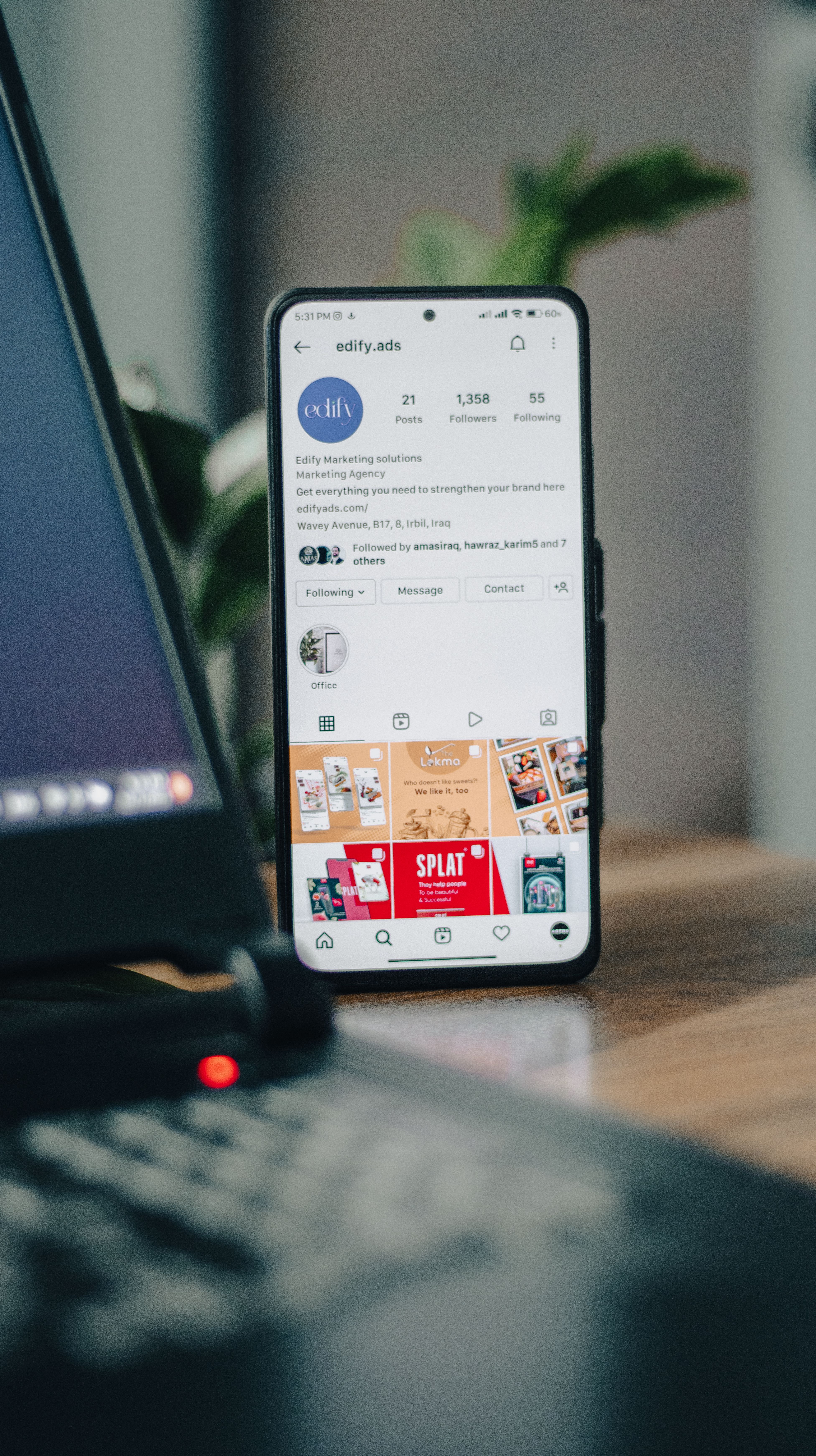Free Vertical shot of a smartphone displaying an Instagram profile next to a laptop, representing social media engagement. Stock Photo