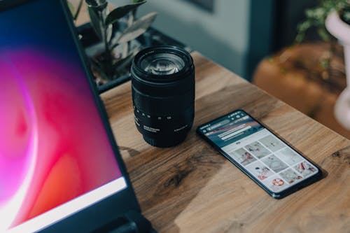 A Mobile Phone Near the Camera Lens on a Wooden Table