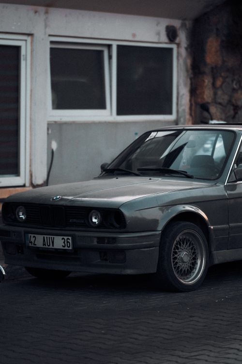 Free An old-fashioned car parked in a gritty urban area, showcasing vintage style. Stock Photo