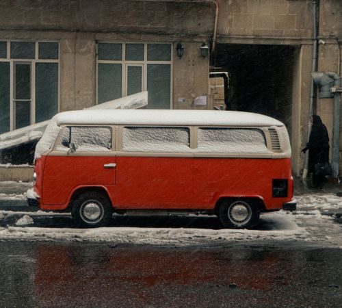 Free A vintage red bus covered in snow parked on an urban street during winter. Stock Photo