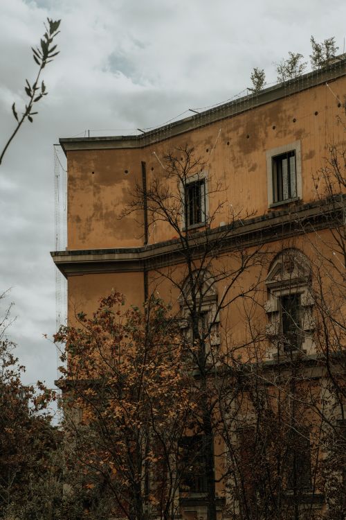 Free A historic villa surrounded by autumn trees under an overcast sky, showcasing classic architecture. Stock Photo