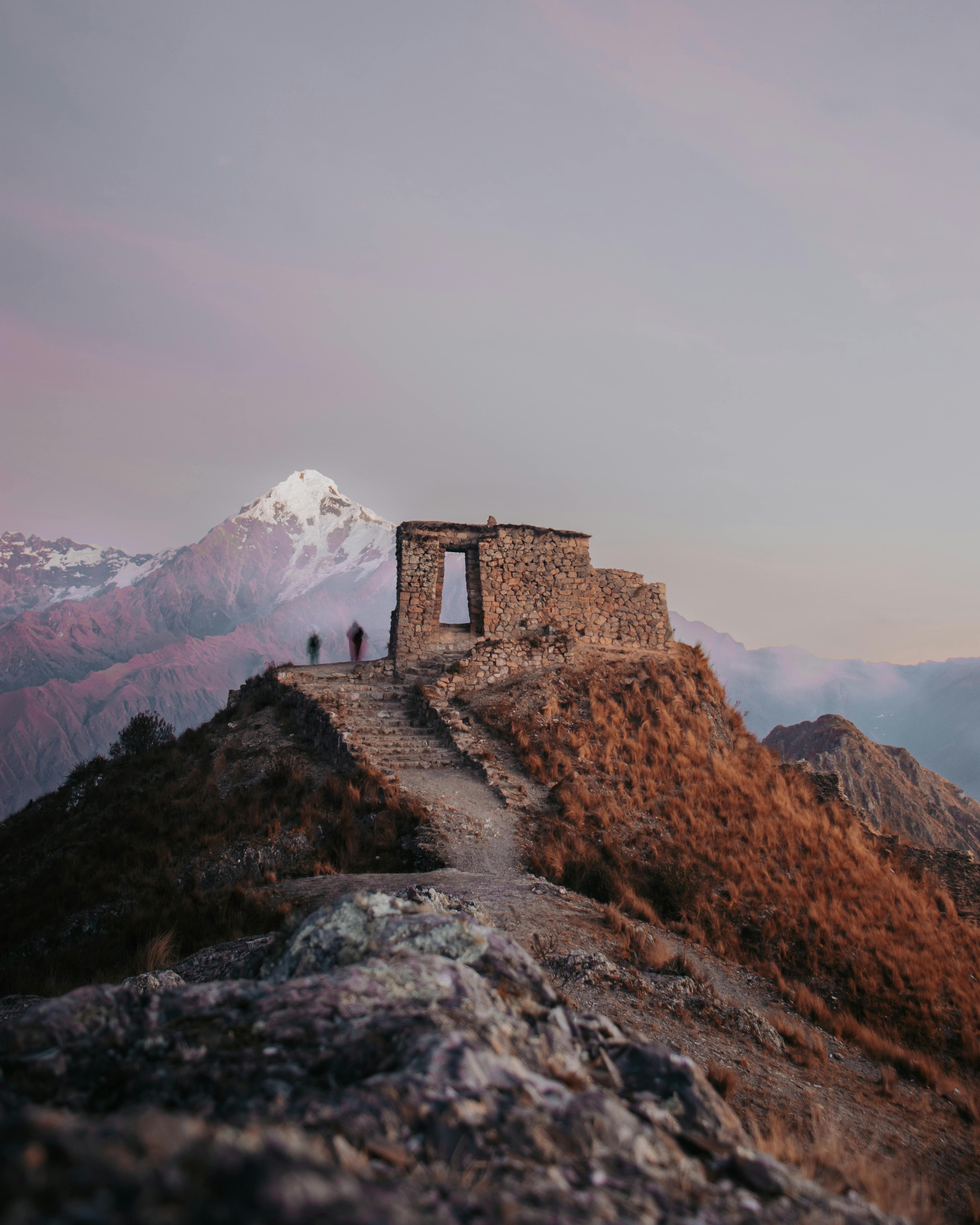 Explore ancient ruins with a stunning mountain backdrop in Urubamba, Peru at sunset.