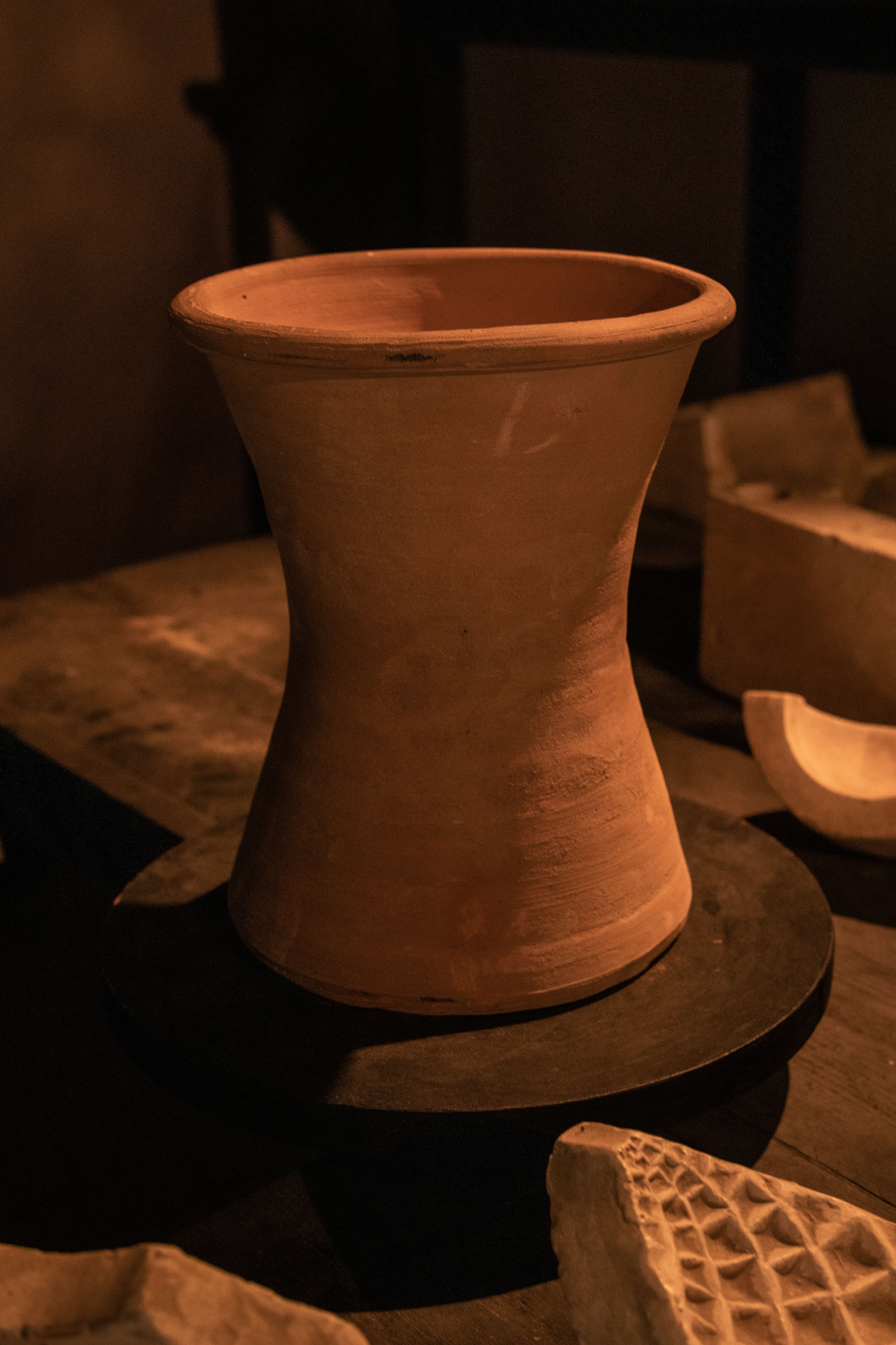 Close-up of a handmade clay vase in a dimly lit artisan studio, emphasizing earthy tones.