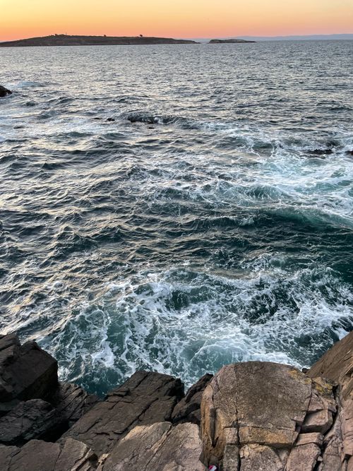Free Captivating view of a rocky coastline with waves and sunset hues. Stock Photo