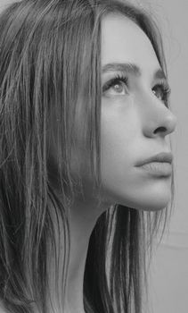 Close-up black and white portrait of a woman looking upwards, capturing a reflective mood.