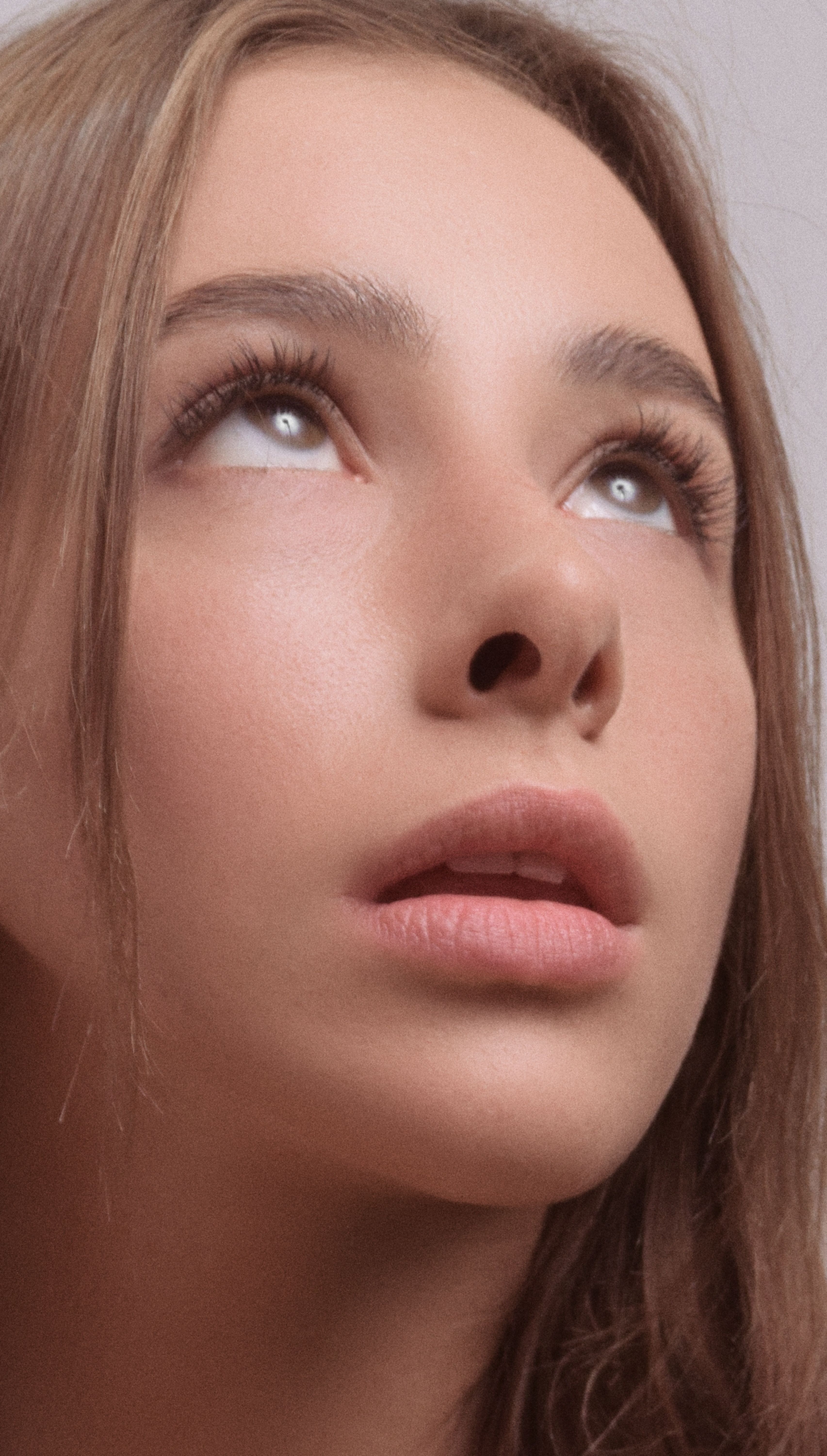 Intimate close-up of a woman looking upward, expressing contemplation and wonder.