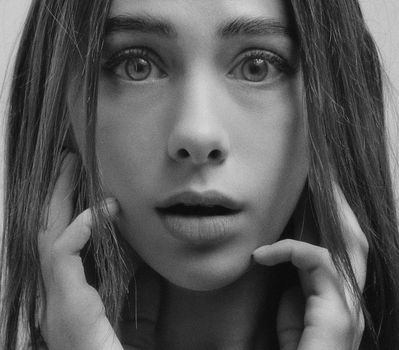 A close-up grayscale portrait capturing the surprised expression of a young woman.