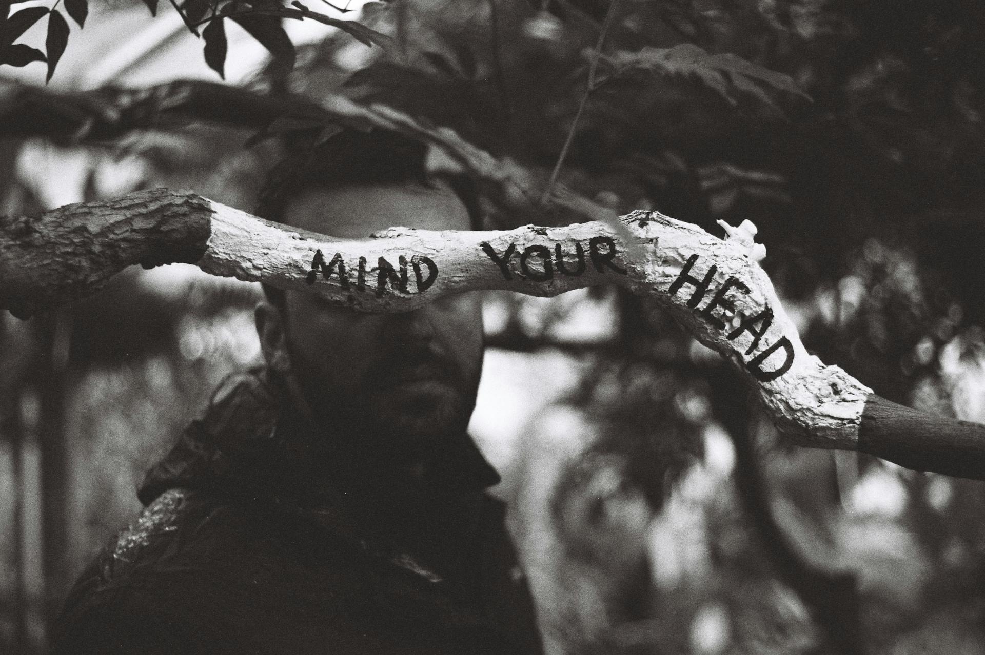 Man Standing Behind a Tree Branch with Caution Sign