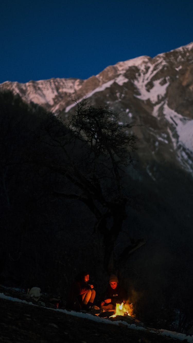 People Camping By Bonfire Near Mountain