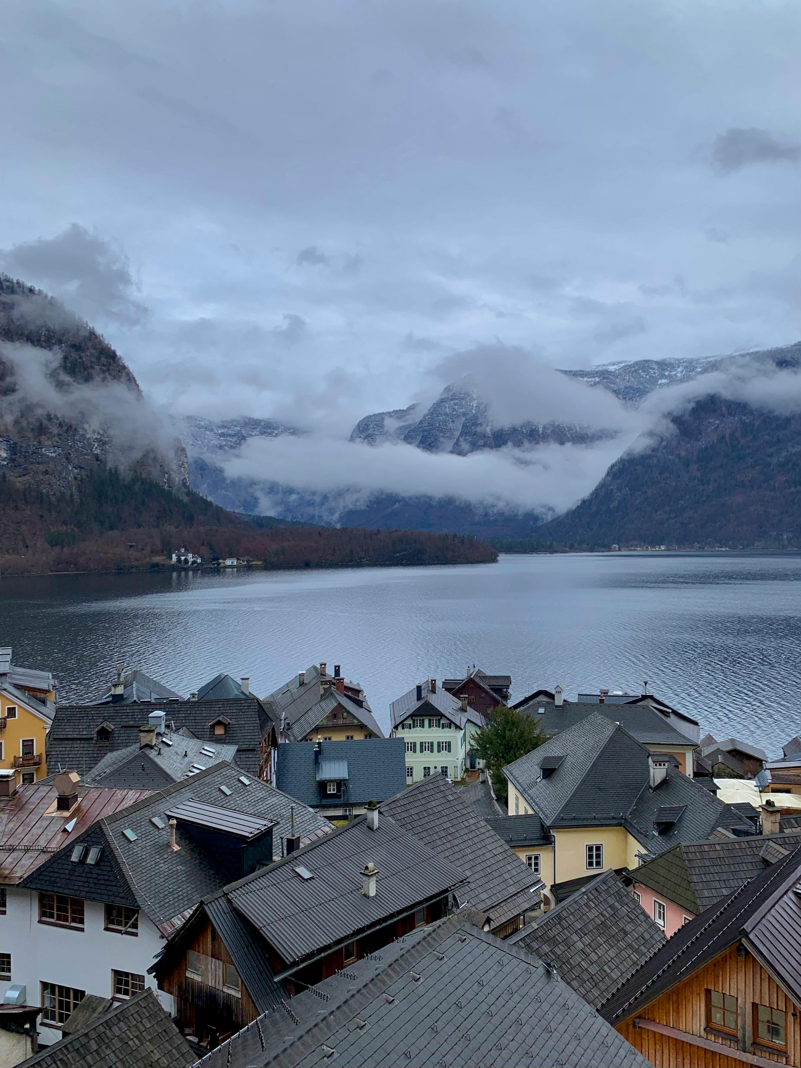 A picturesque view of an alpine village by a tranquil lake with mountains.