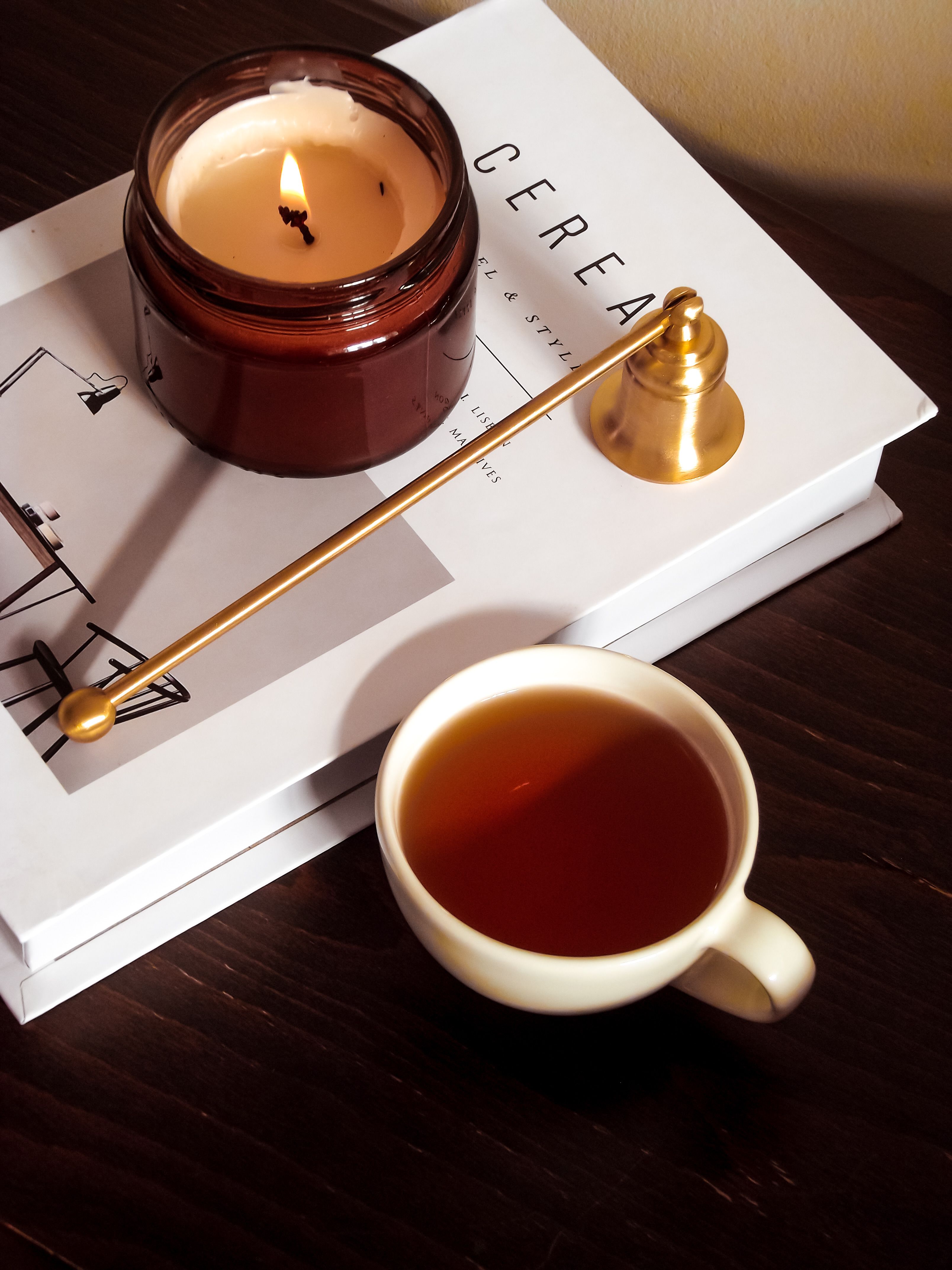 Candle beside a cup of tea in soft warm light