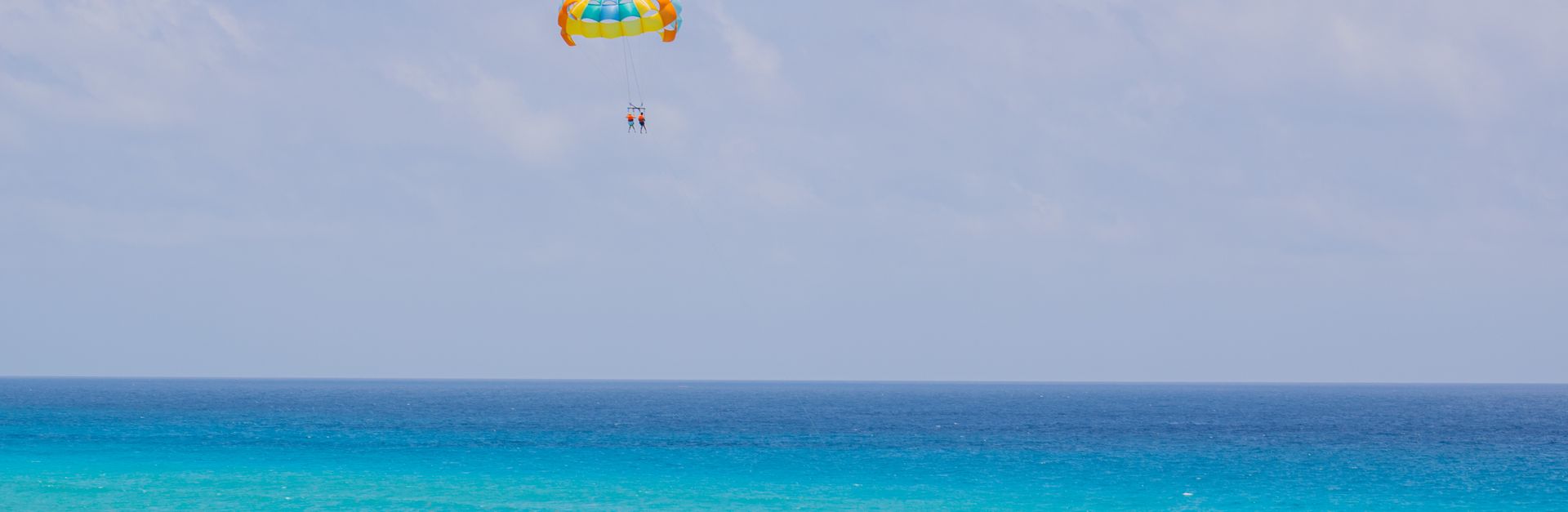 Experience thrilling parasailing above the turquoise sea in Cancún, México. Perfect vacation escape.