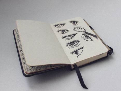 A sketchbook open to a page with artistic eye drawings, showcasing detailed sketches.