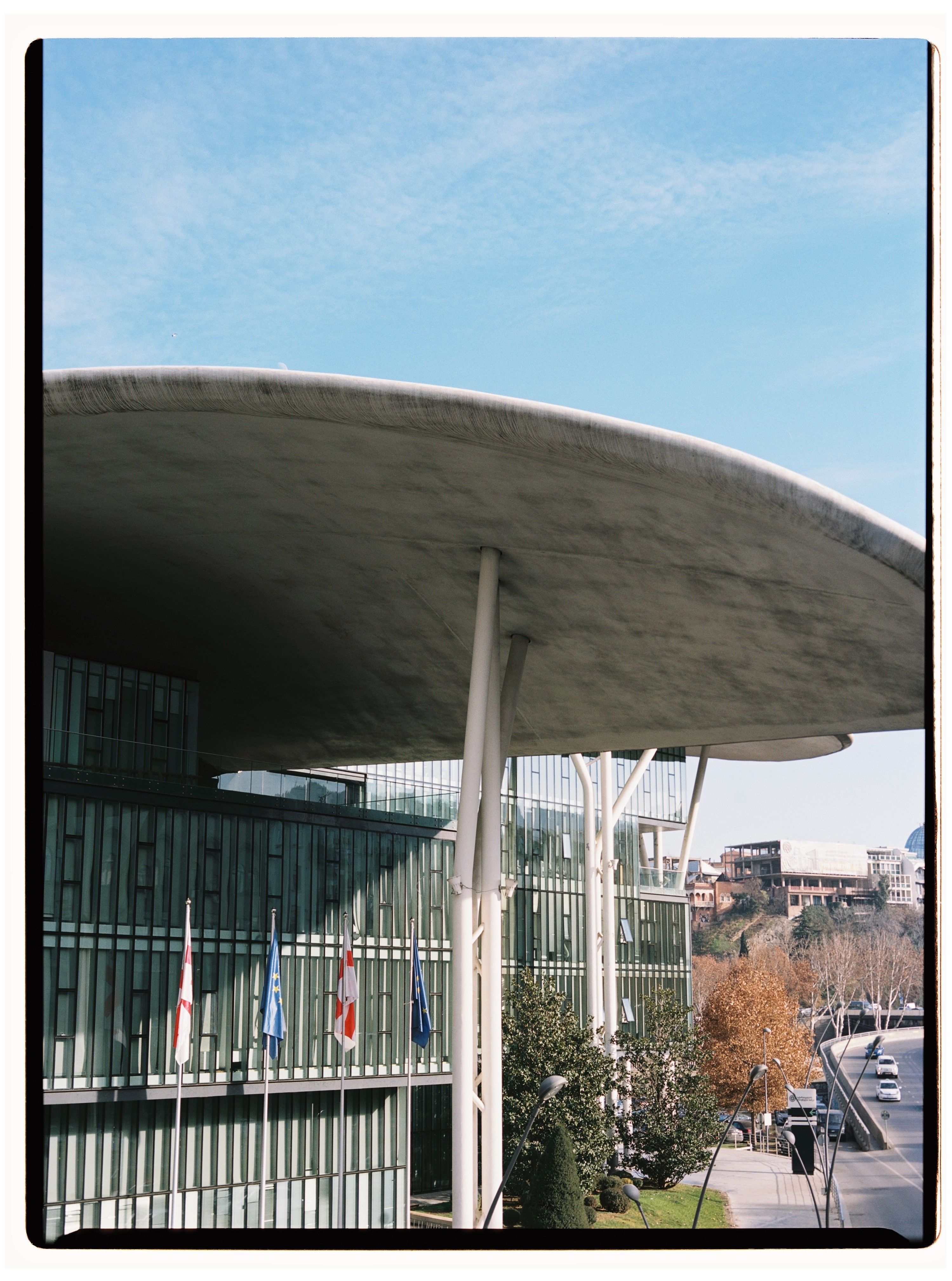 Striking modern architecture featuring the distinctive, wave-shaped roof of a civic building in Tbilisi, Georgia.
