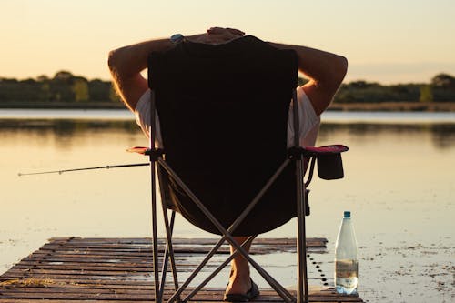 Man Fishing and Relaxing on Chair on Lakeshore