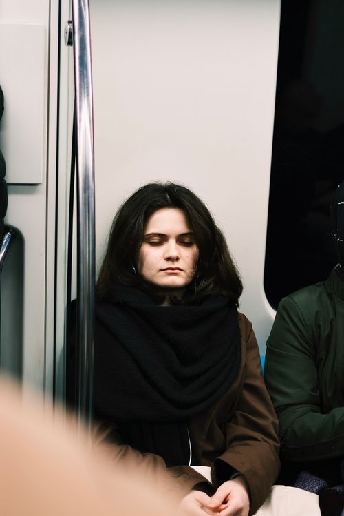 Free A caucasian woman with eyes closed, wearing a scarf, seen sleeping on public transport. Stock Photo