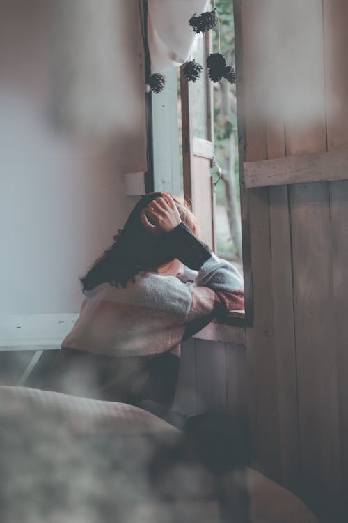 Photo of a Person Leaning on Wooden Window