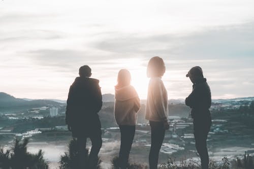 Free Four People Standing on Top of Hill during Sunset Stock Photo