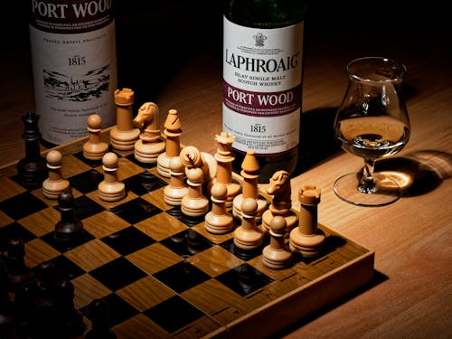 Free A Chess Board and Liquor Bottles on Wooden Table Stock Photo