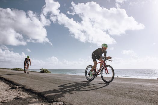 Two cyclists enjoying a ride along a scenic coastal road under a bright sky.