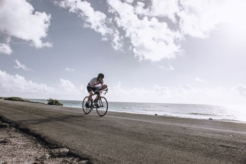 Free A cyclist enjoys a scenic ride by the ocean on a clear, sunny day. Stock Photo