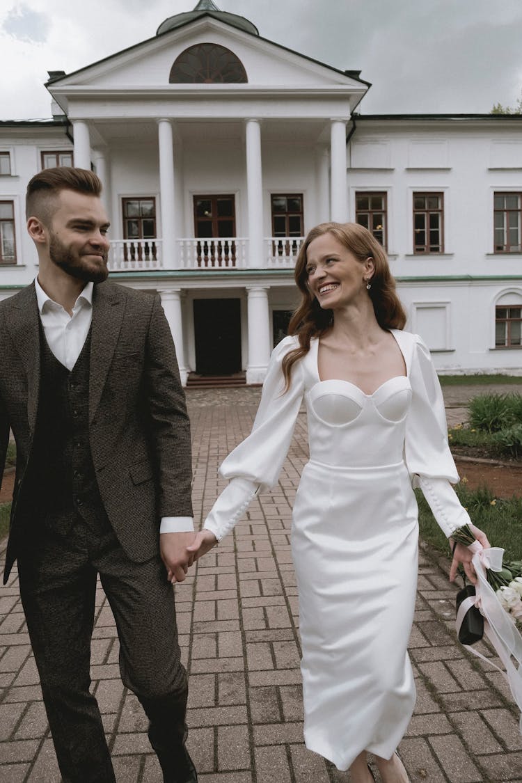 Smiling Bride And Groom Walking Holding Hands