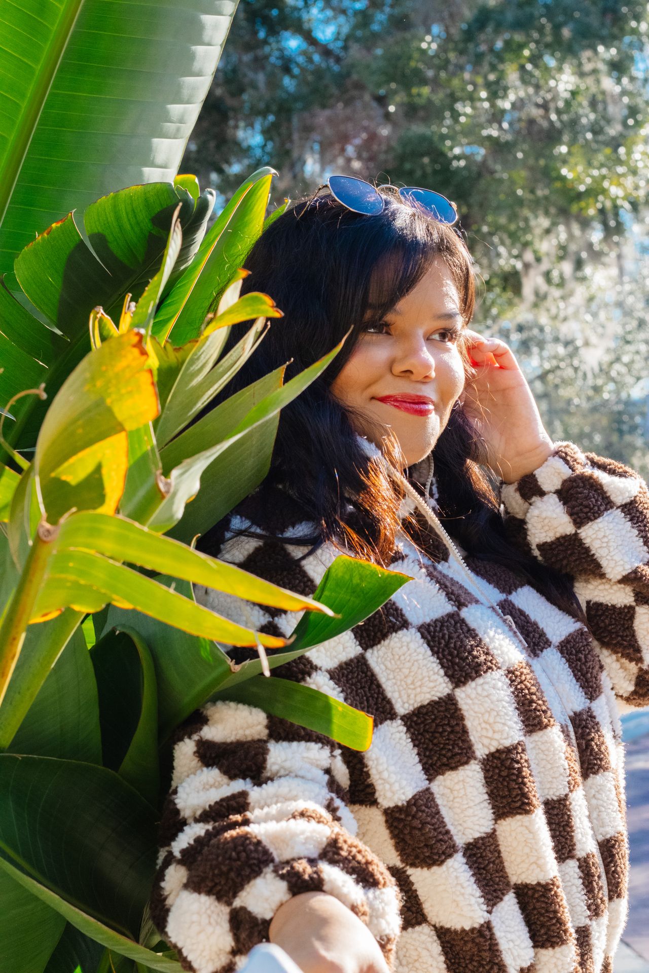 Woman smiling outdoors in a brown and cream checkerboard fleece pullover