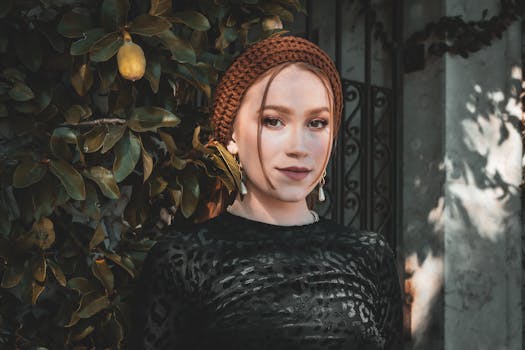 Young woman in a fashionable outfit posing outdoors with leafy background.